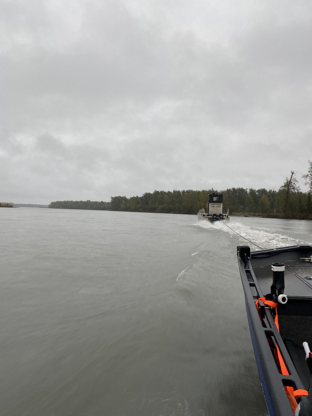 A boat under tow on the Yentna River, tow rope stretching to another boat ahead
