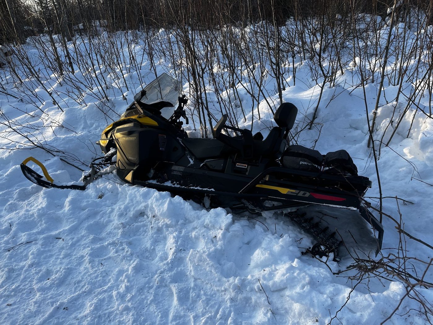 A Ski-Doo Expedition snow machine buried deep in snow among brush