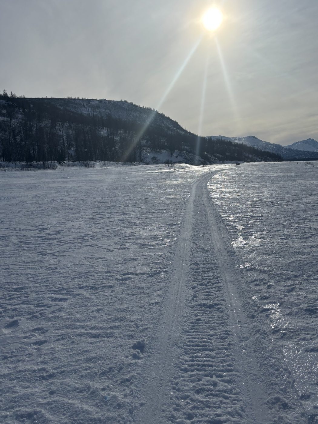A snow machine trail stretching into the distance across a frozen landscape
